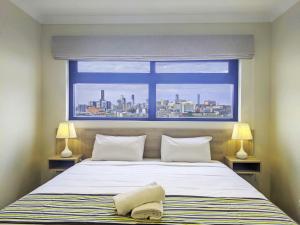 - une chambre avec un grand lit et une fenêtre dans l'établissement The Windsor Hotel Rooms and Apartments, Brisbane, à Brisbane