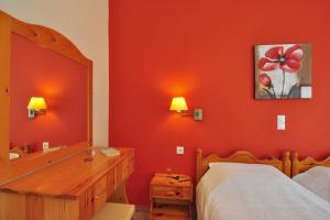 a bedroom with a red wall with a mirror and a bed at Rhea Complex in Paleokastritsa