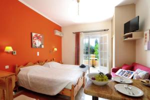 Schlafzimmer mit orangefarbenen Wänden, einem Bett und einem Tisch in der Unterkunft Rhea Complex in Paleokastritsa