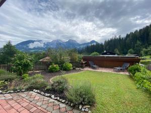 a backyard with a garden with benches and mountains at Ferienwohnung Vorberg in Schönau am Königssee