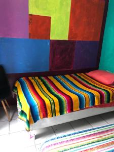 a bed with a multicolored blanket on it at Iguana Hostel Oaxaca in Oaxaca City
