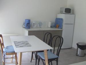 eine Küche mit einem Tisch und Stühlen sowie einem Kühlschrank in der Unterkunft Gîte les Hortensias in Beauquesne