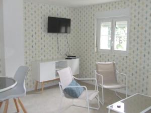 a room with chairs and a table and a tv on a wall at Gîte les Hortensias in Beauquesne