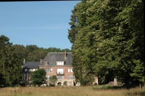 a large brick house in the middle of trees at Gîte les Hortensias in Beauquesne