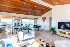 a living room with wood ceilings and a kitchen and dining room at Ocean View in Te Whau Bay