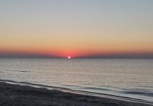 una puesta de sol sobre el océano con una playa en Casa Laura, en Corbu