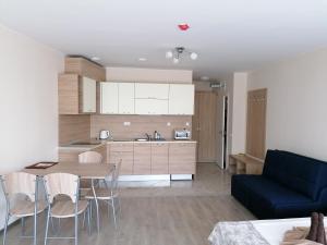 a kitchen and living room with a table and a blue couch at Apart Allure Dobi in Primorsko