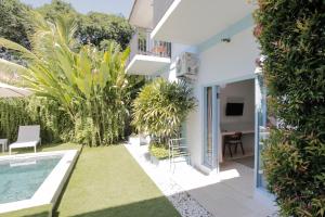 a garden with a pool and a house at Gatsby Hotel Hostel in Uluwatu