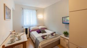 um pequeno quarto com uma cama e uma televisão em Miriam Rooms Zadar em Zadar