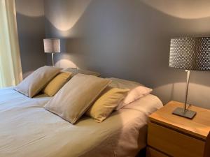 a bed with pillows and a table with a lamp at Appartement Standing 55m2 - Terrasse Sud, Parking, Wifi in Aix-les-Bains