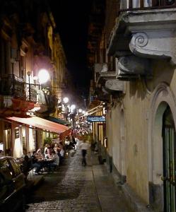 Una calle de la ciudad por la noche con gente caminando por la calle en Casa Nipitella, en Catania