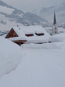un edificio cubierto de nieve junto a una iglesia en dolomit24 | design apARTments en Sillian