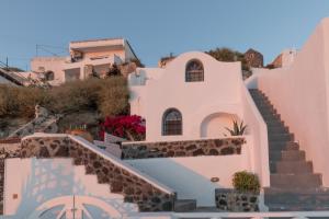 a white house with stairs and flowers on a hill at Folia Bianca Apartments in Imerovigli