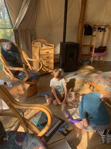 Dos niños sentados en el suelo en una habitación en Glamping Drzwi Do Lasu en Supraśl