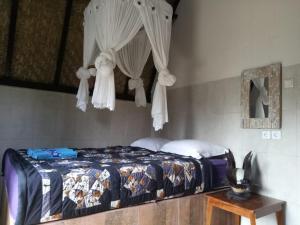 a bedroom with a bed with curtains and a table at Zelobi Omnivora Cottage in Kintamani