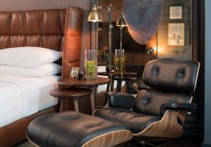 a bedroom with a bed and a pair of leather chairs at Hotel AKA Boston Common in Boston