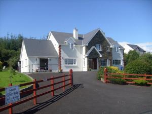 uma grande casa branca com uma cerca em frente em Sneem River Lodge Bed & Breakfast em Sneem