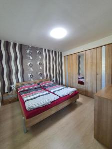a bedroom with a bed with a striped wall at Apartmán Kurdějov in Hustopeče +45 photos