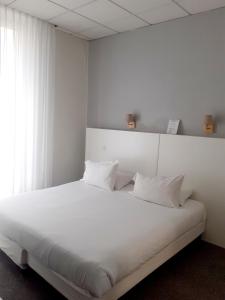 a white bed with white pillows in a room at Hôtel P.L.M. in Cannes