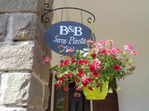 a flower pot hanging from a building with a sign at B&B Serra Pineta in Serramazzoni