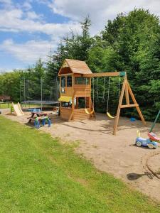 a playground with a house and a swing at Domki Letniskowe Pola in Ryn