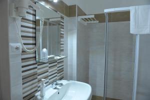 un bagno bianco con lavandino e doccia di Albergo " il Gattopardo" di Esposito Carmela & C sas a SantʼArcangelo
