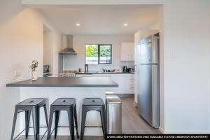 a kitchen with a refrigerator and stools in it at The Willows Wanaka in Wanaka