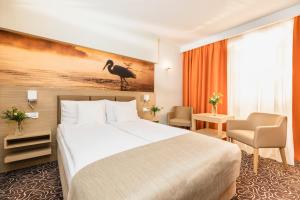 a hotel room with a bed and a bird on the wall at Hotel Amazonka Conference and Spa in Ciechocinek