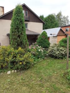 einen Garten mit Büschen und ein Haus in der Unterkunft IOMAN HAUS in Ikšķile