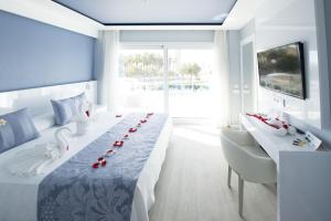 a bedroom with a long table with red roses on it at Masd Mediterraneo Hotel Apartamentos Spa in Castelldefels