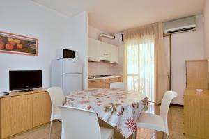 eine kleine Küche mit einem Tisch und Stühlen sowie einem Kühlschrank in der Unterkunft Residenza Canova in Lignano Sabbiadoro