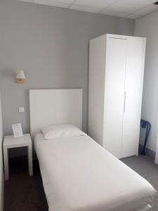 a bedroom with a white bed and a cabinet at Hôtel P.L.M. in Cannes