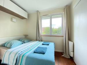 una camera da letto con un letto con lenzuola blu e una finestra di Appart'Village Jouy Les Metz a Jouy-en-Josas