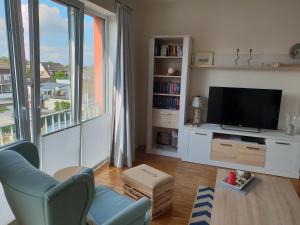 een woonkamer met een tv en een groot raam bij Ferienwohnung Caprinus in Büsum