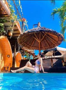 a woman in a bikini sitting under an umbrella in a swimming pool at Mi Lan Boutique Resort in Vung Tau +17 photos