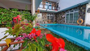 a house with a swimming pool and flowers in the yard at Villa Paradise Rodrigues in Rodrigues Island