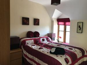 a bedroom with a bed with a red and white blanket at Peacock Cottage, Coity Bach in Talybont