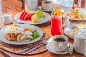 a table with plates of breakfast foods and a cup of coffee at Green Zone Ubud Villas by Pramana Villas in Ubud