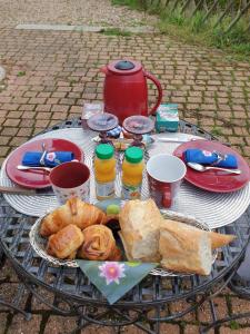 una mesa con una bandeja de pan y bollería. en Chambre d’hôte Normande, en Freneuse-sur-Risle