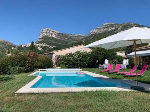 a swimming pool with pink chairs and an umbrella at Bed & Breakfast Les LILLAS in Saint-Jeannet