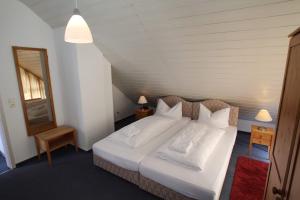 Hotel Garni Am Schäfersberg في نيدرنهاوسن: غرفة نوم بسرير كبير عليها شراشف ووسائد بيضاء