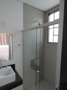 uma casa de banho com um chuveiro e um lavatório. em Hotel Picpo em Ponte Nova