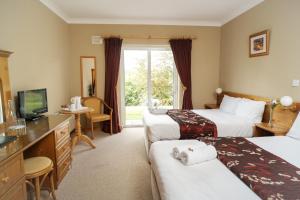een hotelkamer met twee bedden en een televisie bij Ardilaun Guesthouse Self Catering in Ennis