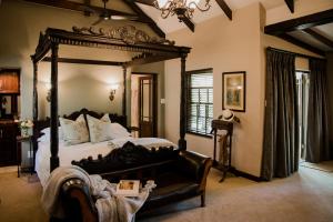 a bedroom with a large canopy bed and a chair at Schoone Oordt Country House in Swellendam