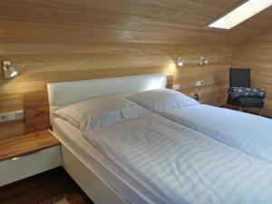 a bedroom with a large bed with a wooden wall at Ferienwohnung auf der Scheibe in Bezau