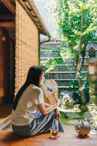 a woman sitting on the floor holding a fan at Guest House Hitsujian in Kyoto