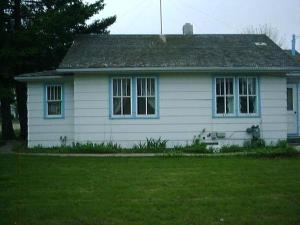 a white house with two windows and a grass yard at Holiday Cottage in Canora