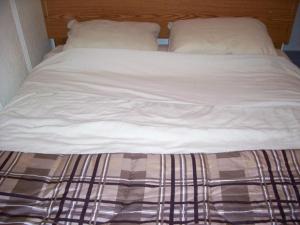 1 cama no hecha con sábanas y almohadas blancas en Holiday Cottage en Canora