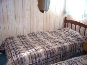 a bed with a plaid comforter in a bedroom at Holiday Cottage in Canora