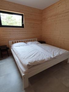 a white bed in a wooden room with a window at Piaski Rogowa in Rogowo
